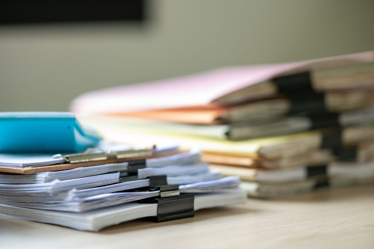 Stack of documents with paper clip folder placed on a business desk in a business office.