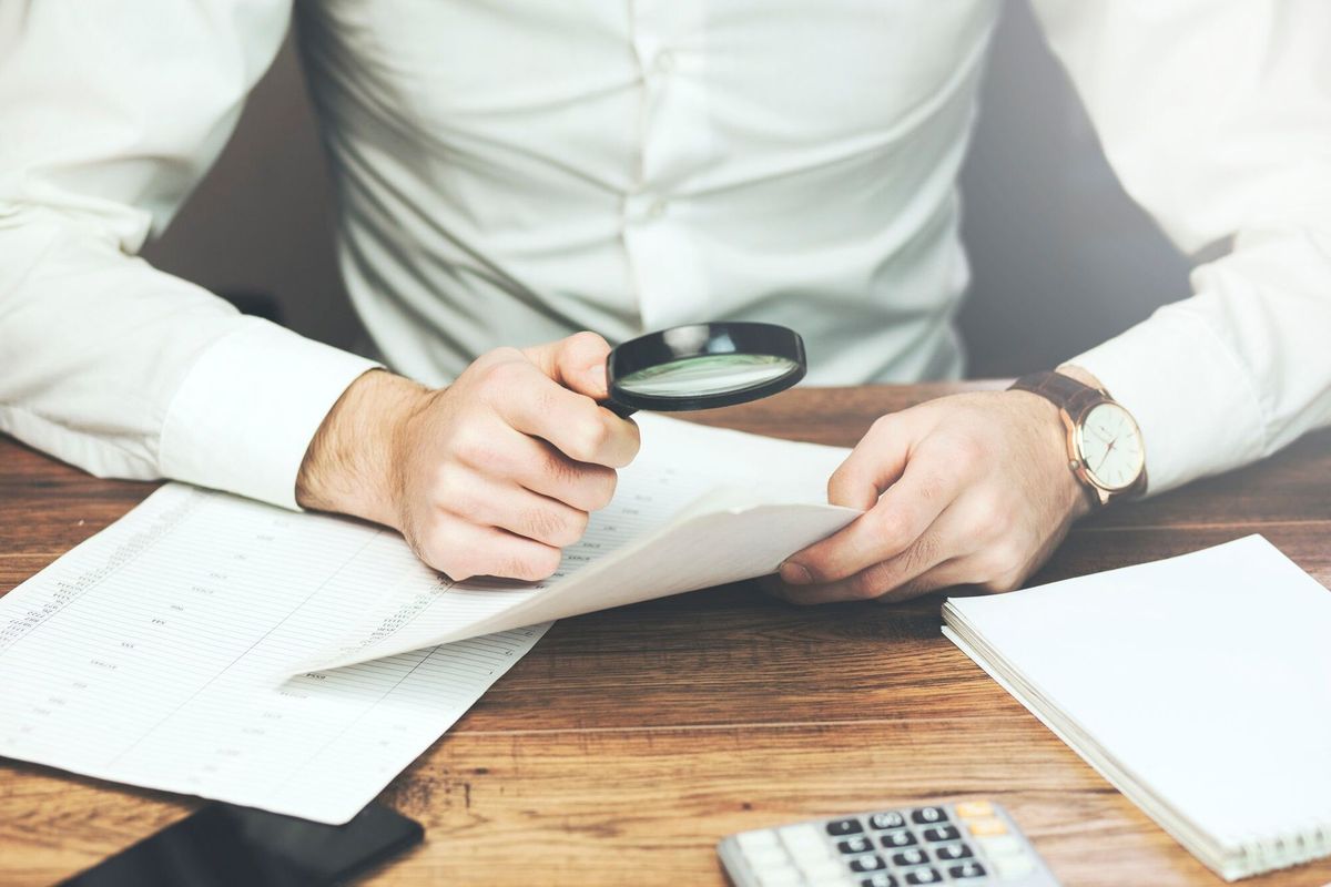 Business man reading documents with magnifying glass