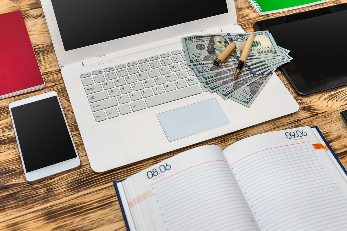 Dollar banknotes on pc keyboard and empty notepad