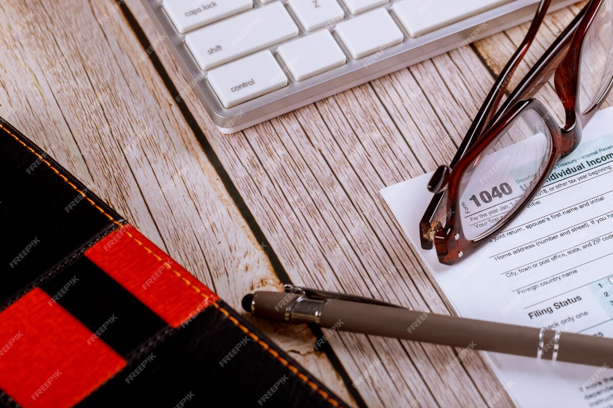 Workplace office desk table in the accountant's office U.S. income tax 1040 form with glasses and pen on the computer keyboard