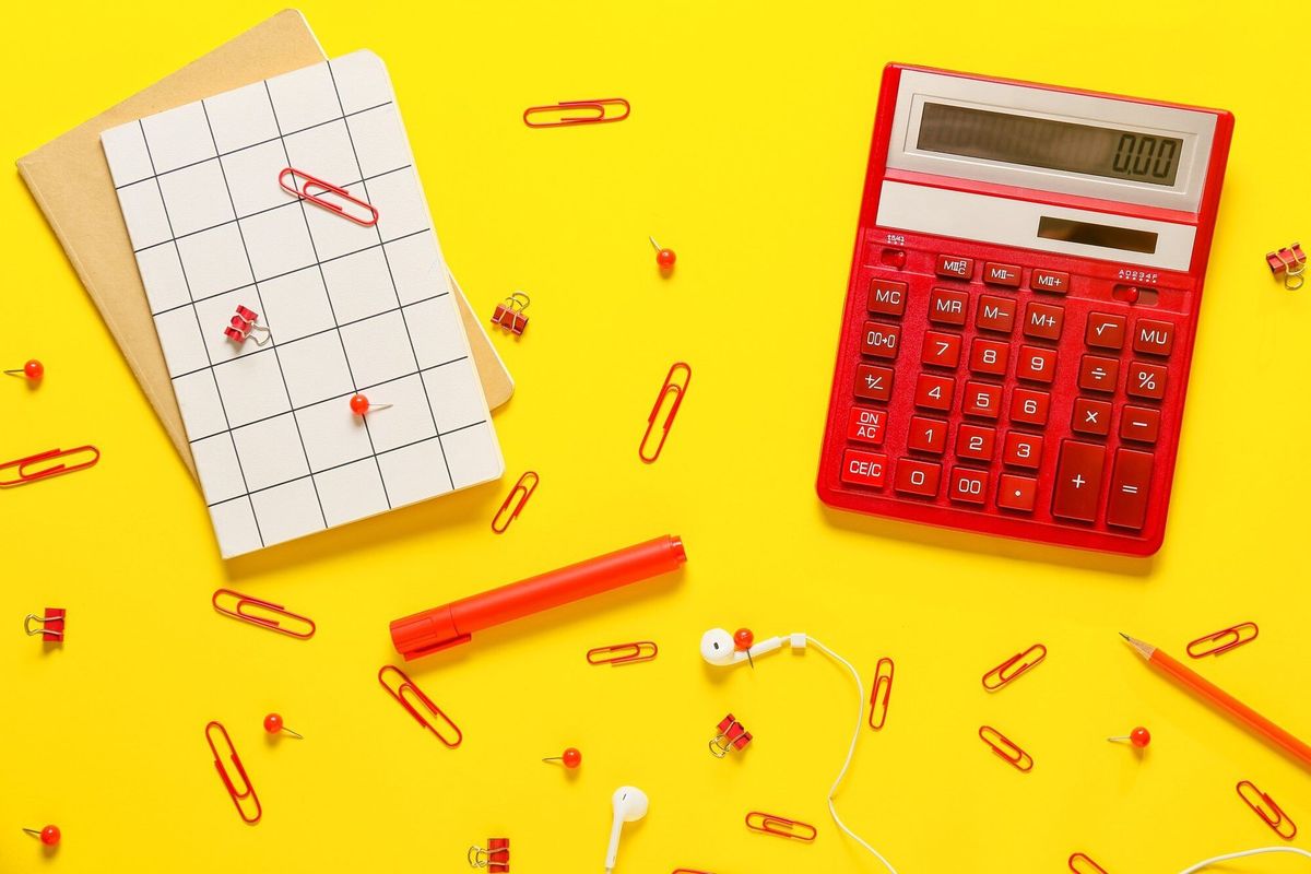 Modern calculator and stationery on color surface